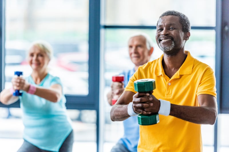 Man smiling in an exercise class, because he knows exercise increases his gut microbiome.