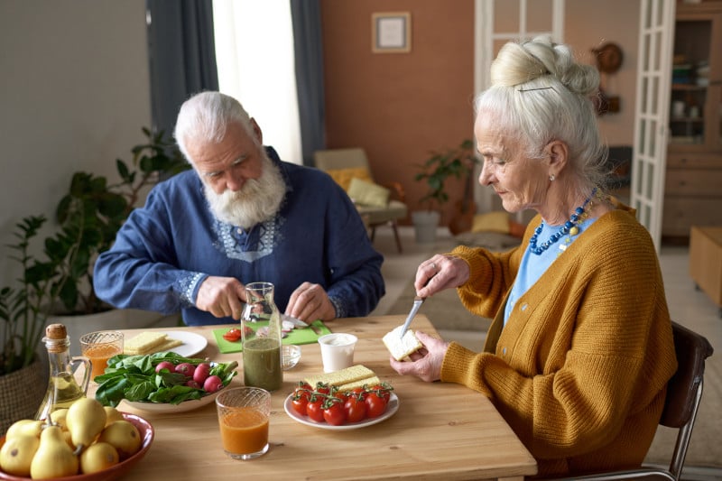 Senior couple having a nutrient dense breakfast together, supporting their gut microbiome and alleviating autoimmune pain. 