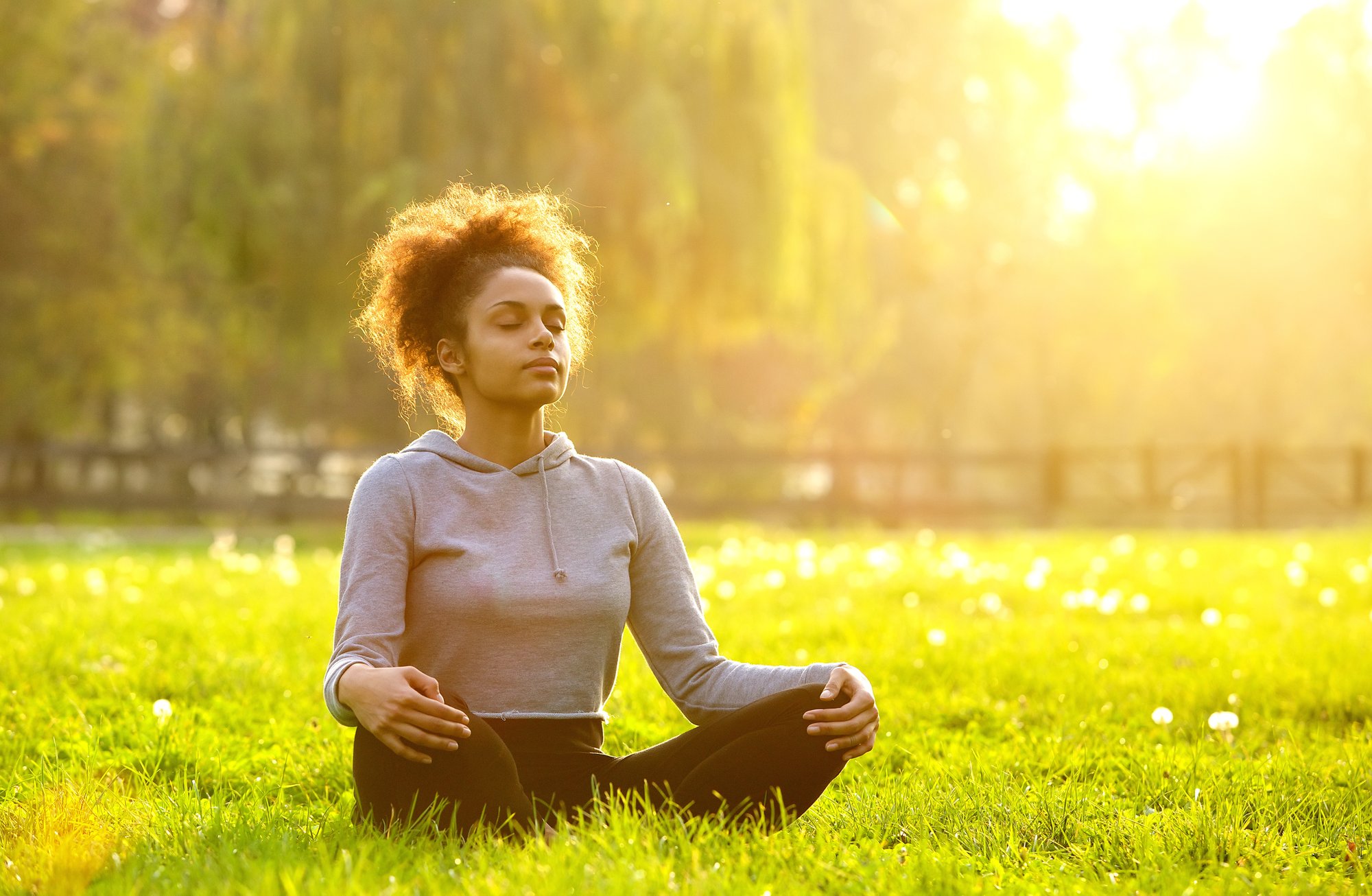 Women meditating outside in the sunshine, helping her immune system regulate properly.