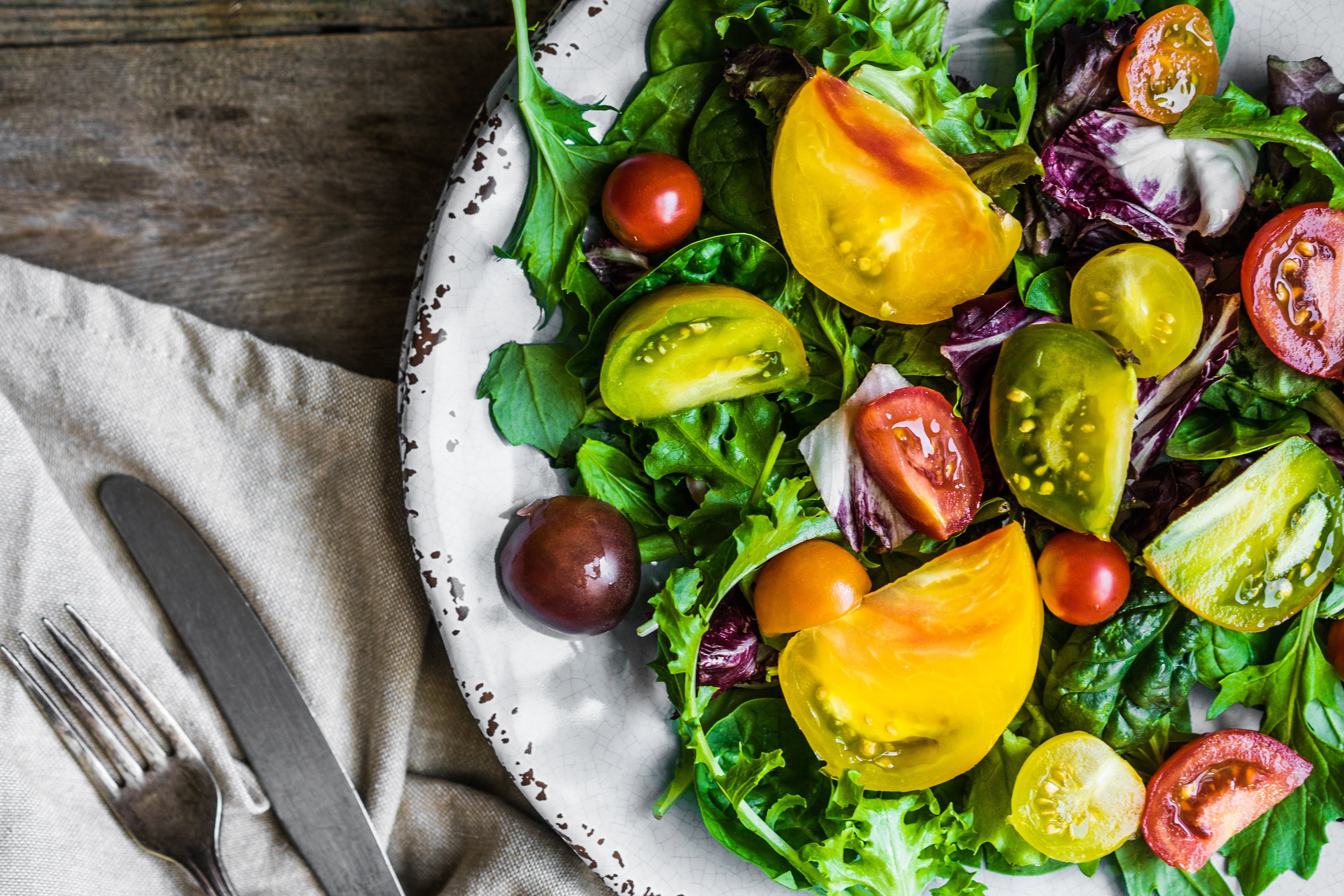 A beautiful plate of green salad and heirloom tomatoes, great for the  keto diet.