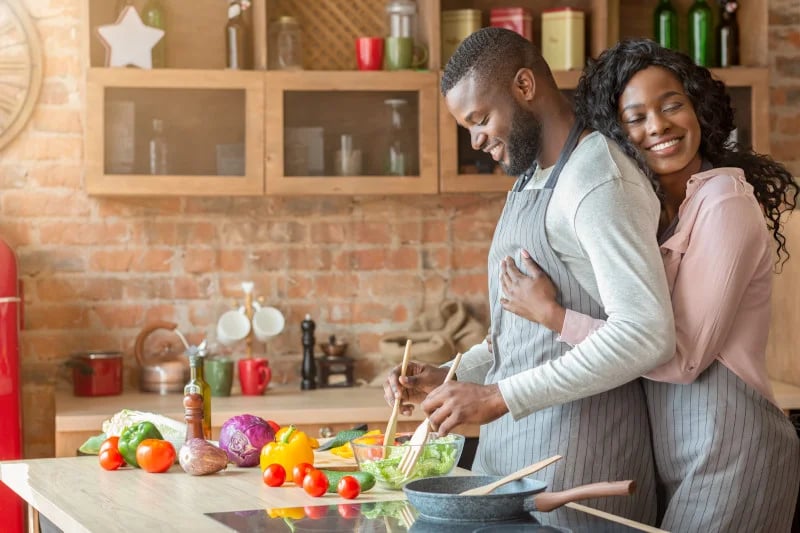 Couple in a kitchem smiling and hugging because they are happy to have functional medicine reducing their GI disorders.