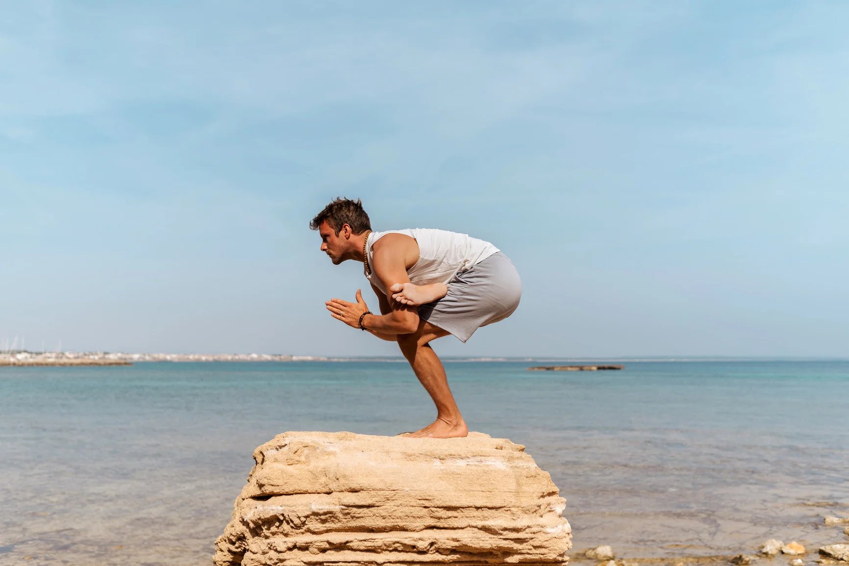 Man balancing in a yoga pose on a rock overlooking the ocean and using the polyvagal theory to help his PTSD