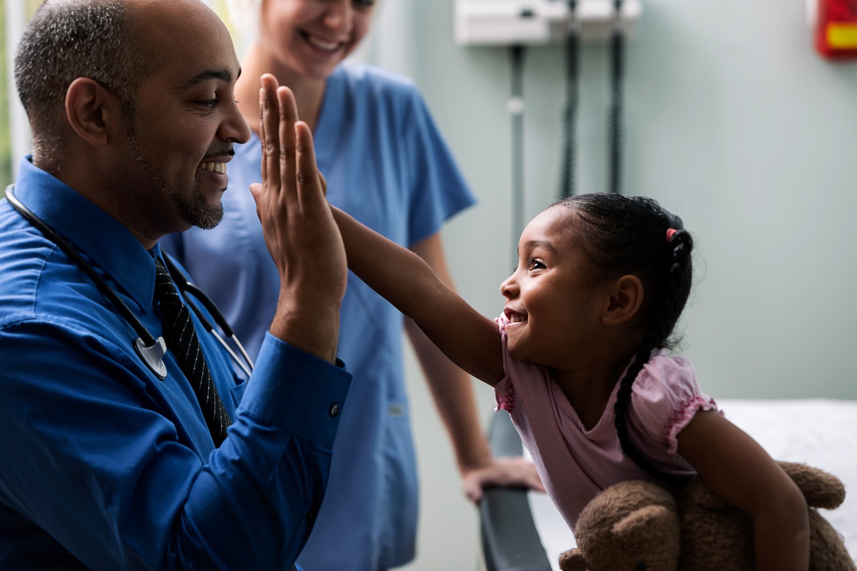 Physician high-fiving pediatric patient in an exam room  