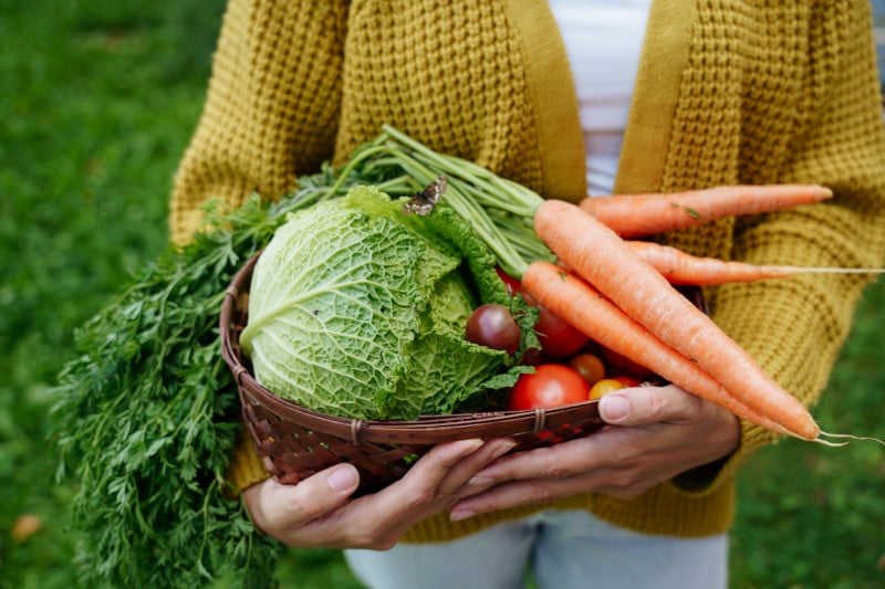 Close up of a women holding a basket full of vegetables as she applies functional medicine and nutrition into practice